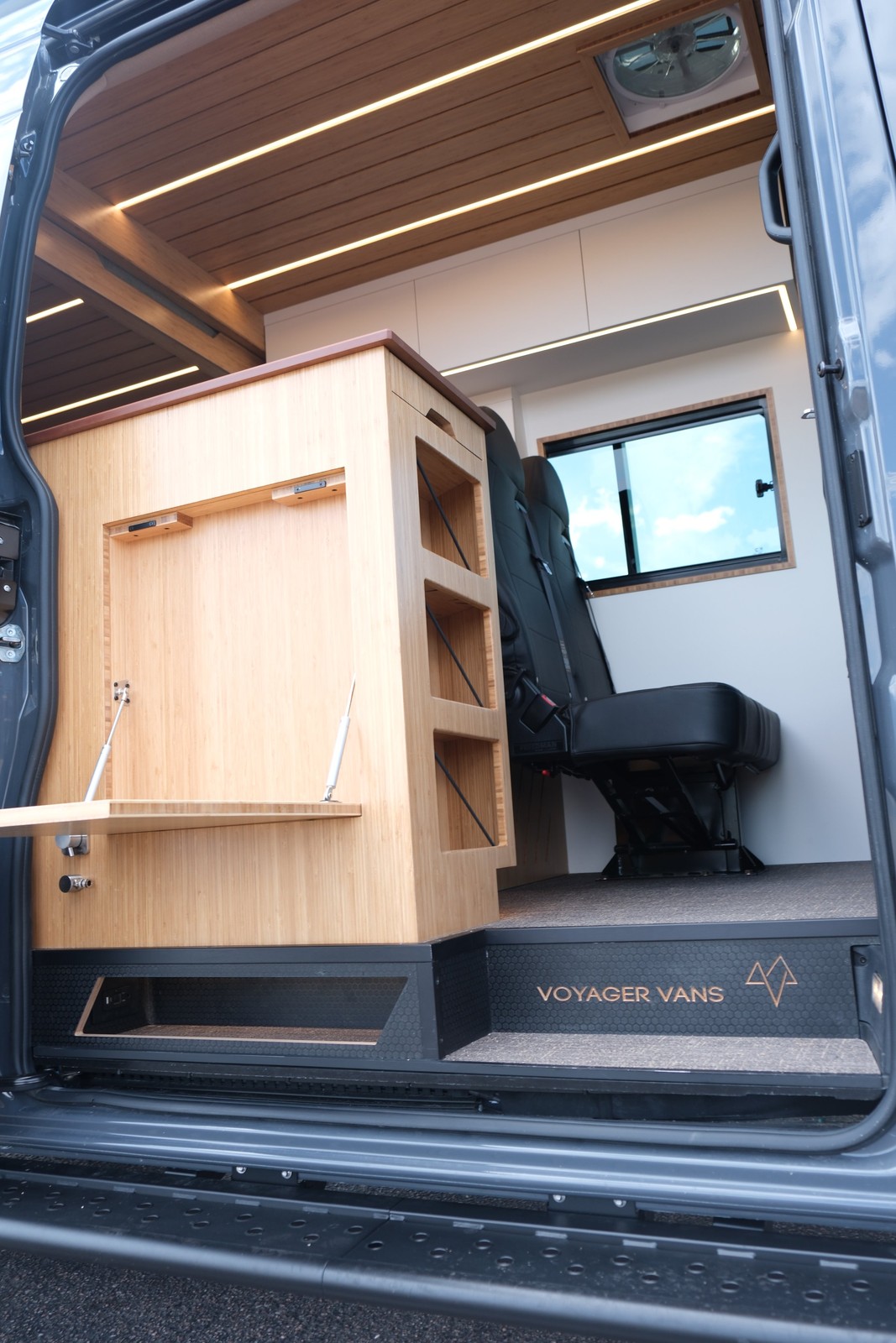 The Den open side entry showing the fold-down table, galley cabinetry and second-row seats.