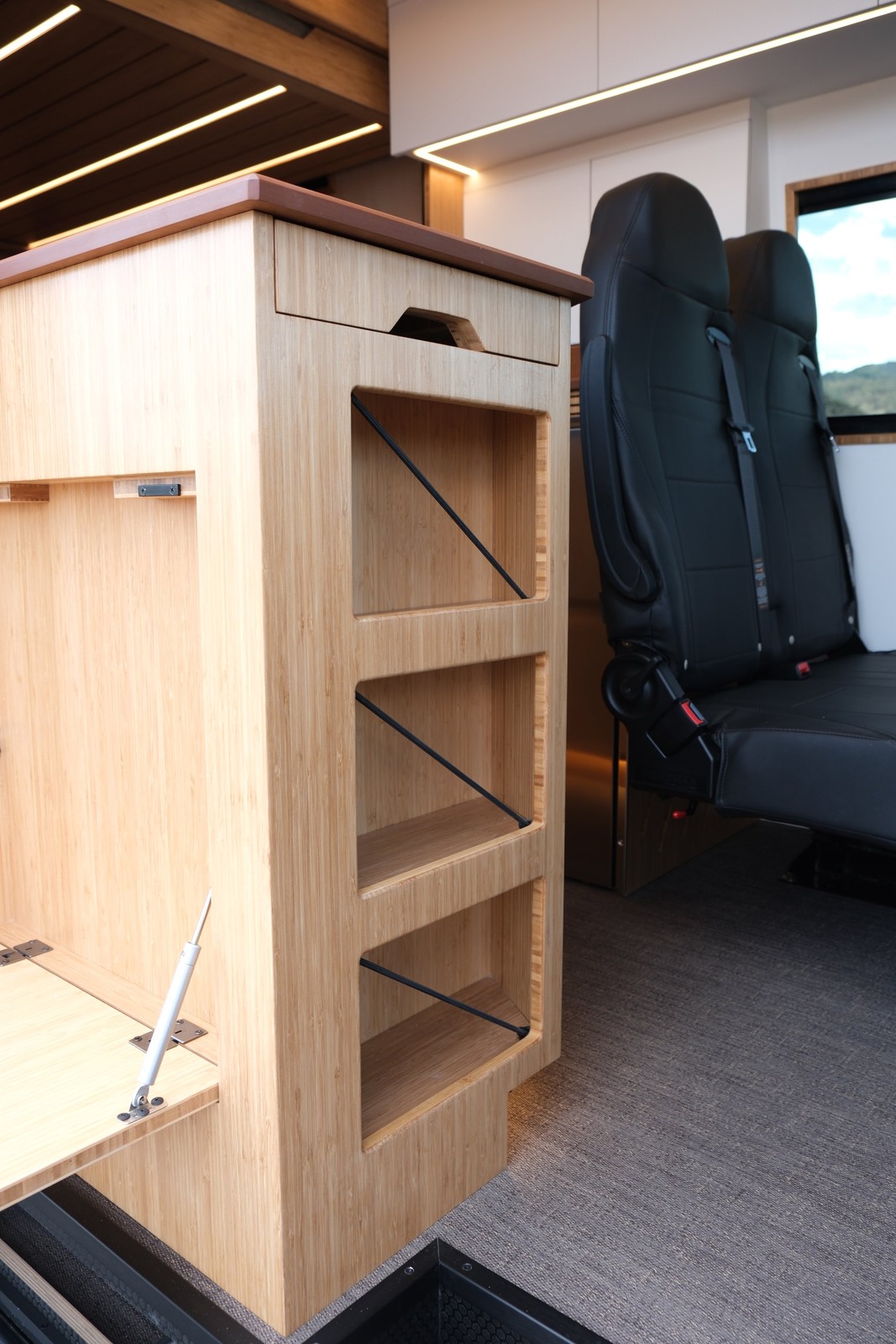 Detail of the Den side-entry cabinet with open shelving beside the passenger bench.