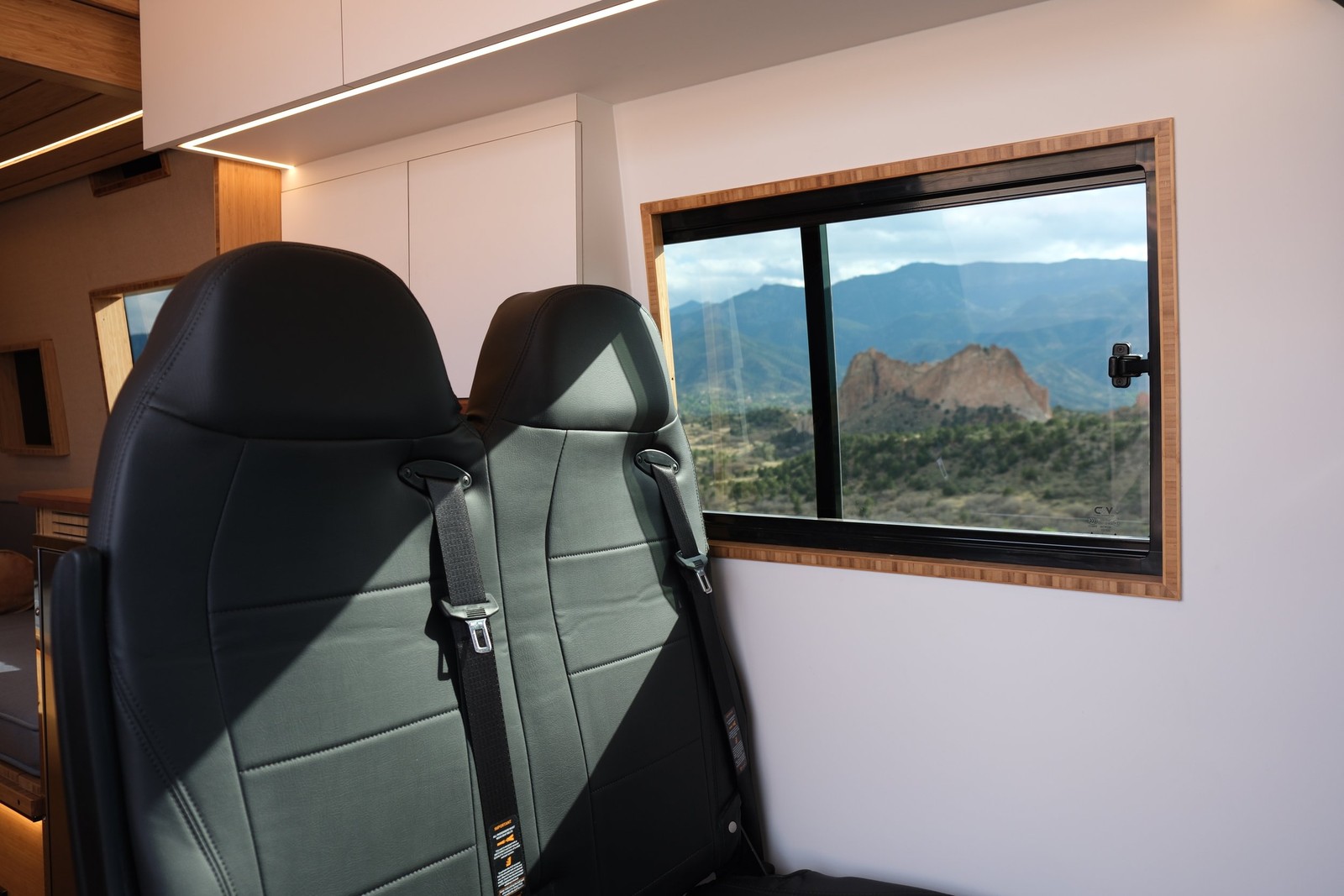 The Den two-person passenger bench beneath a window with a mountain view.