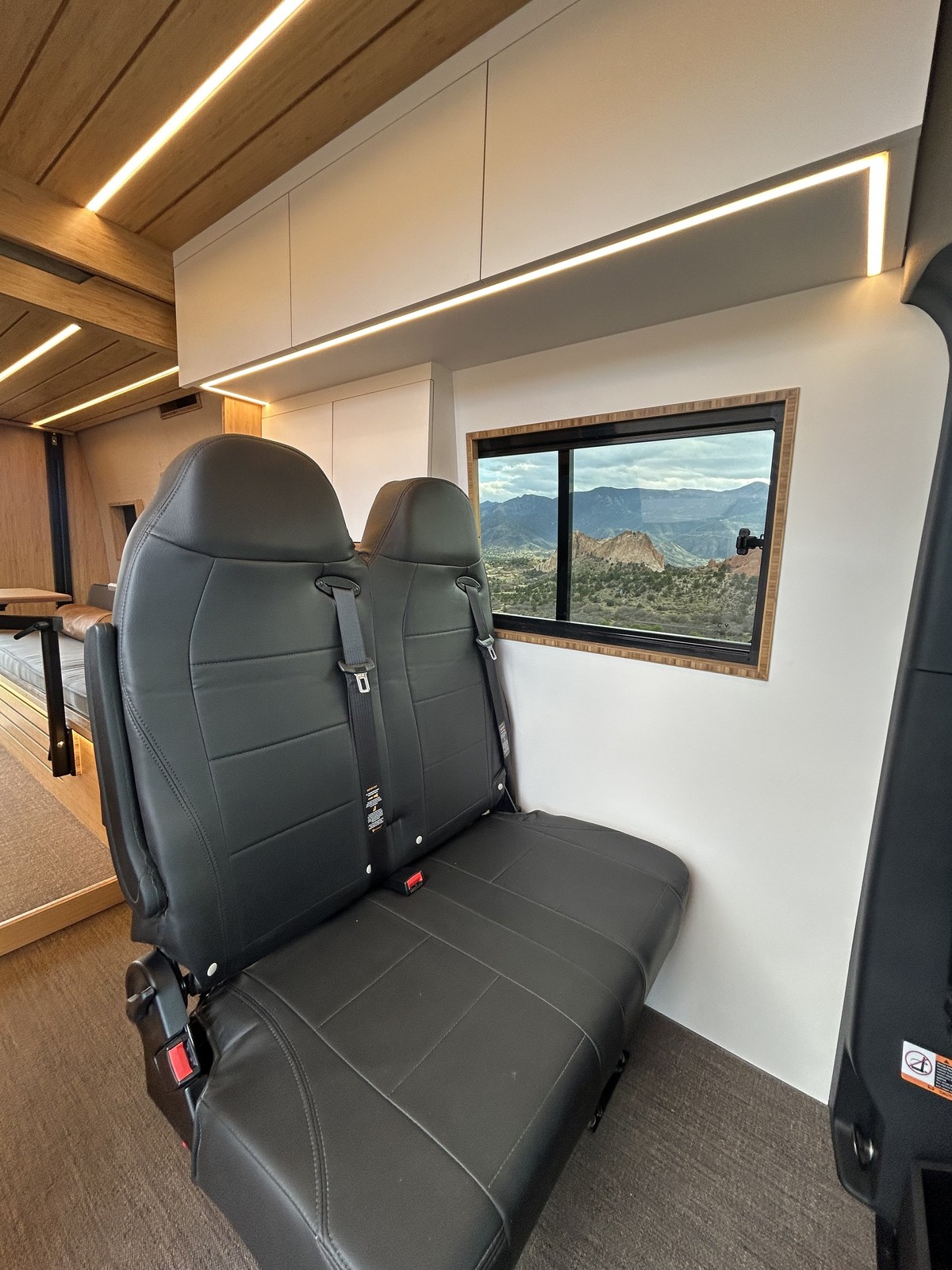 The Den second-row bench beneath white overhead cabinets and a wood slat ceiling.