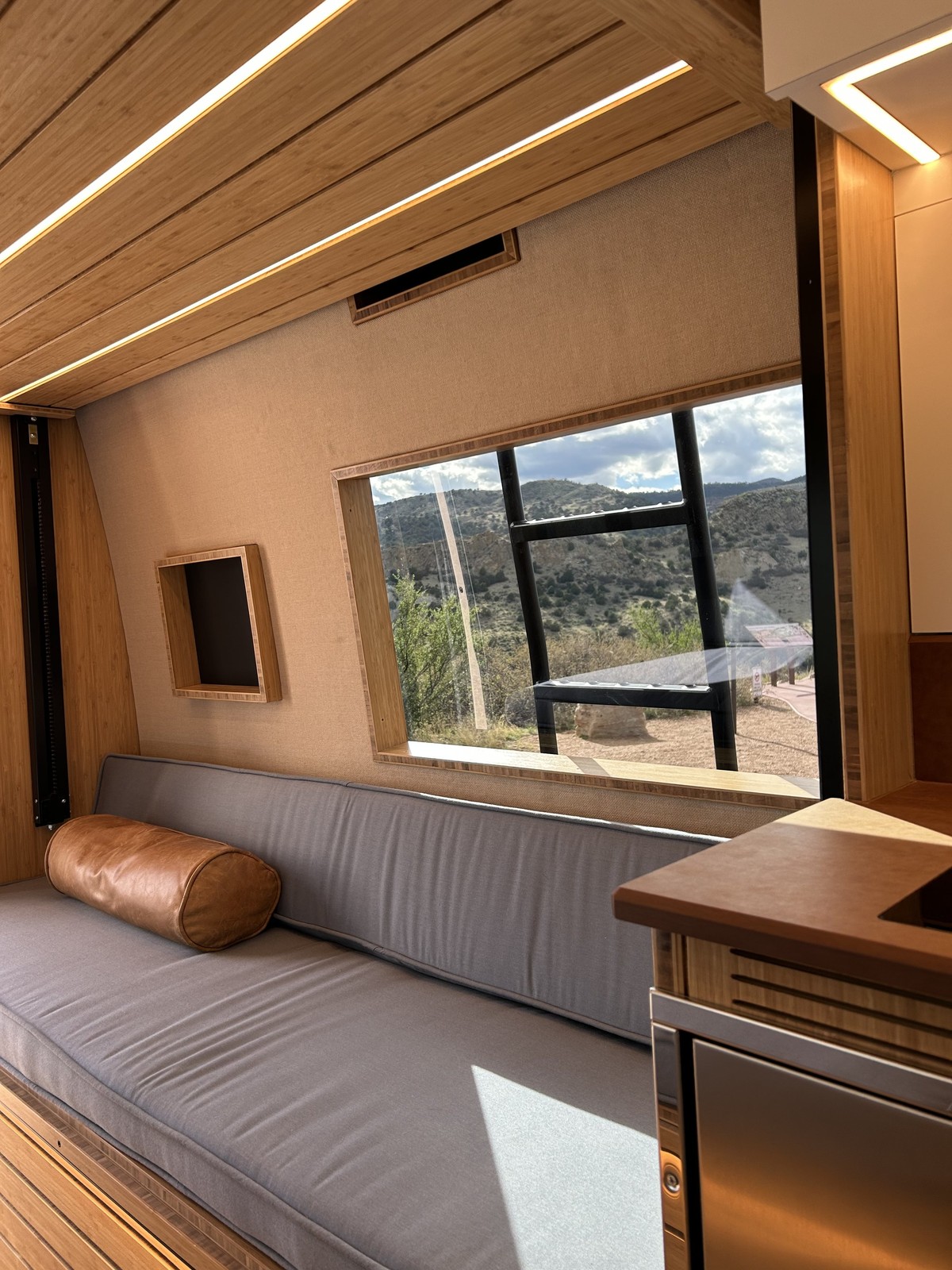 The Den upholstered lounge bench beneath a wide window and raised elevator bed.