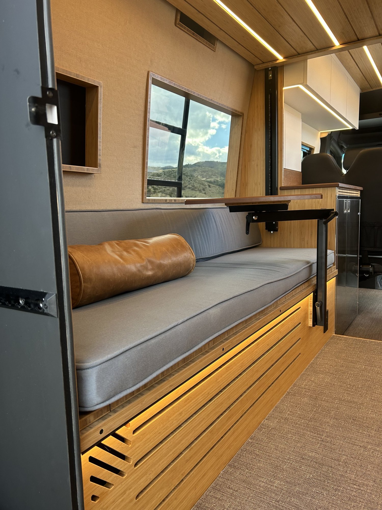 The Den cushioned bench below a large window, with wood trim and warm floor lighting.