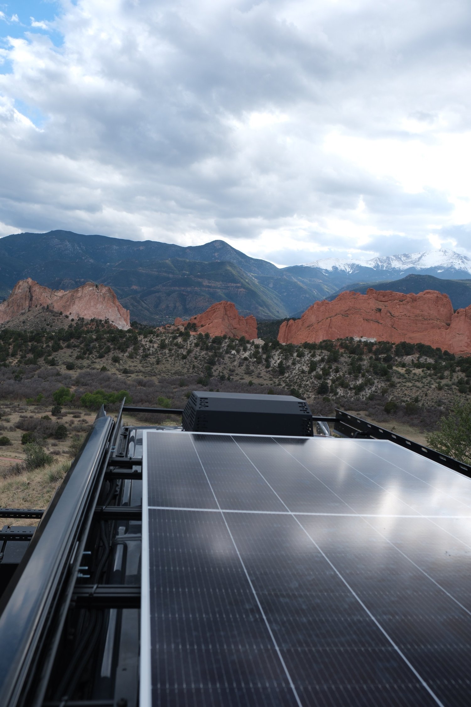 The Den rooftop solar panels with red rock formations and mountains beyond.