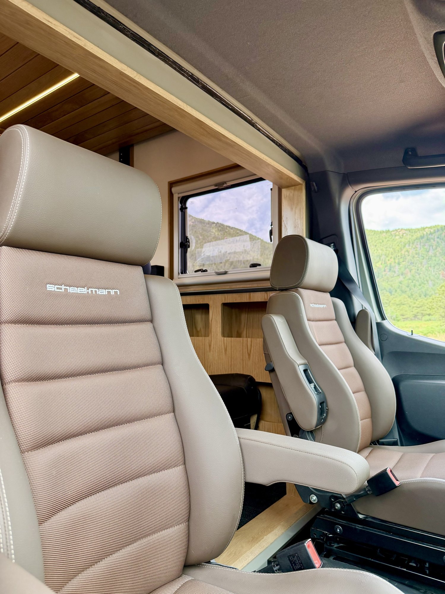 Two light-colored captain’s chairs in the Nest cab beneath wood trim.