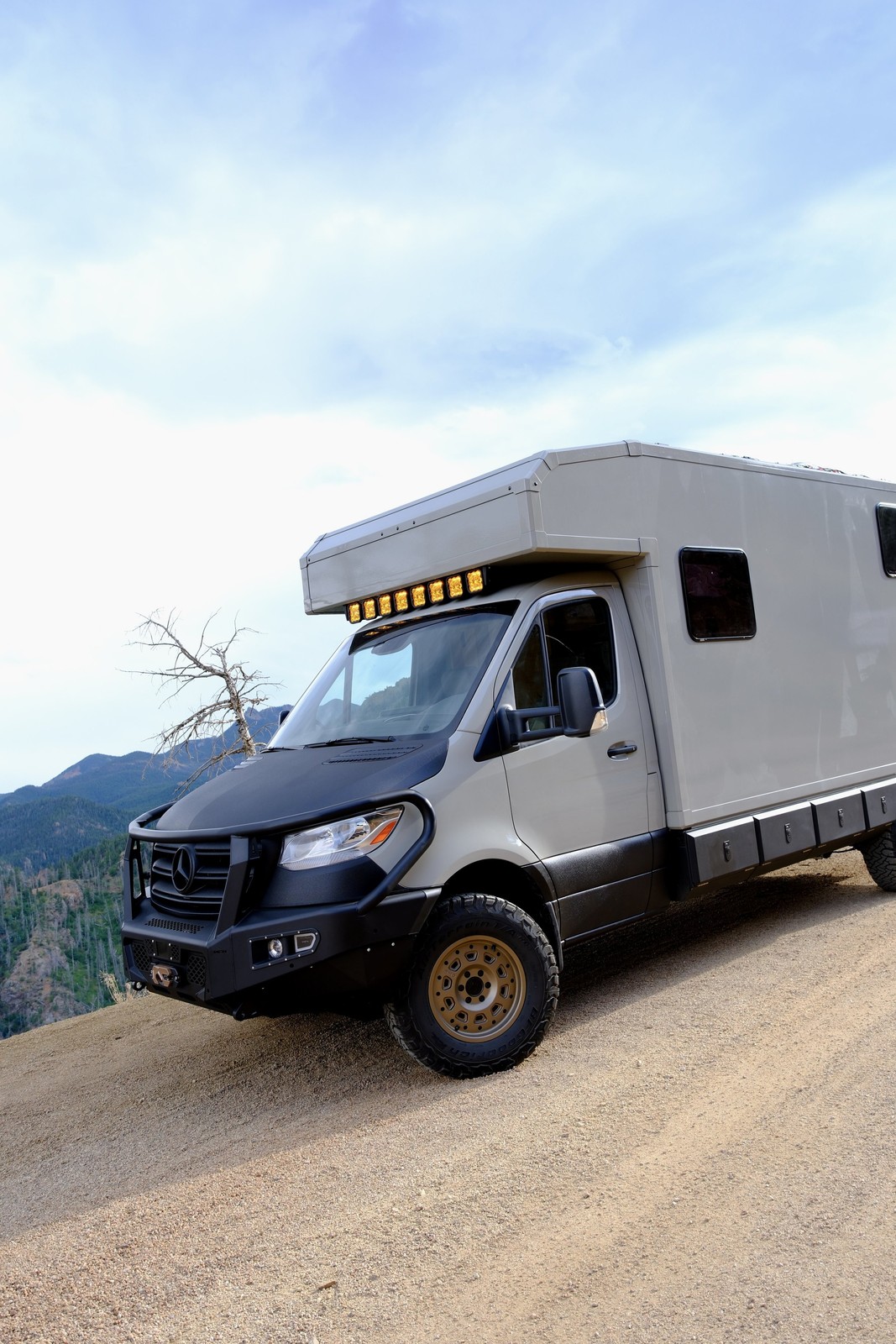 The Nest composite-body adventure vehicle parked beside a mountain road.
