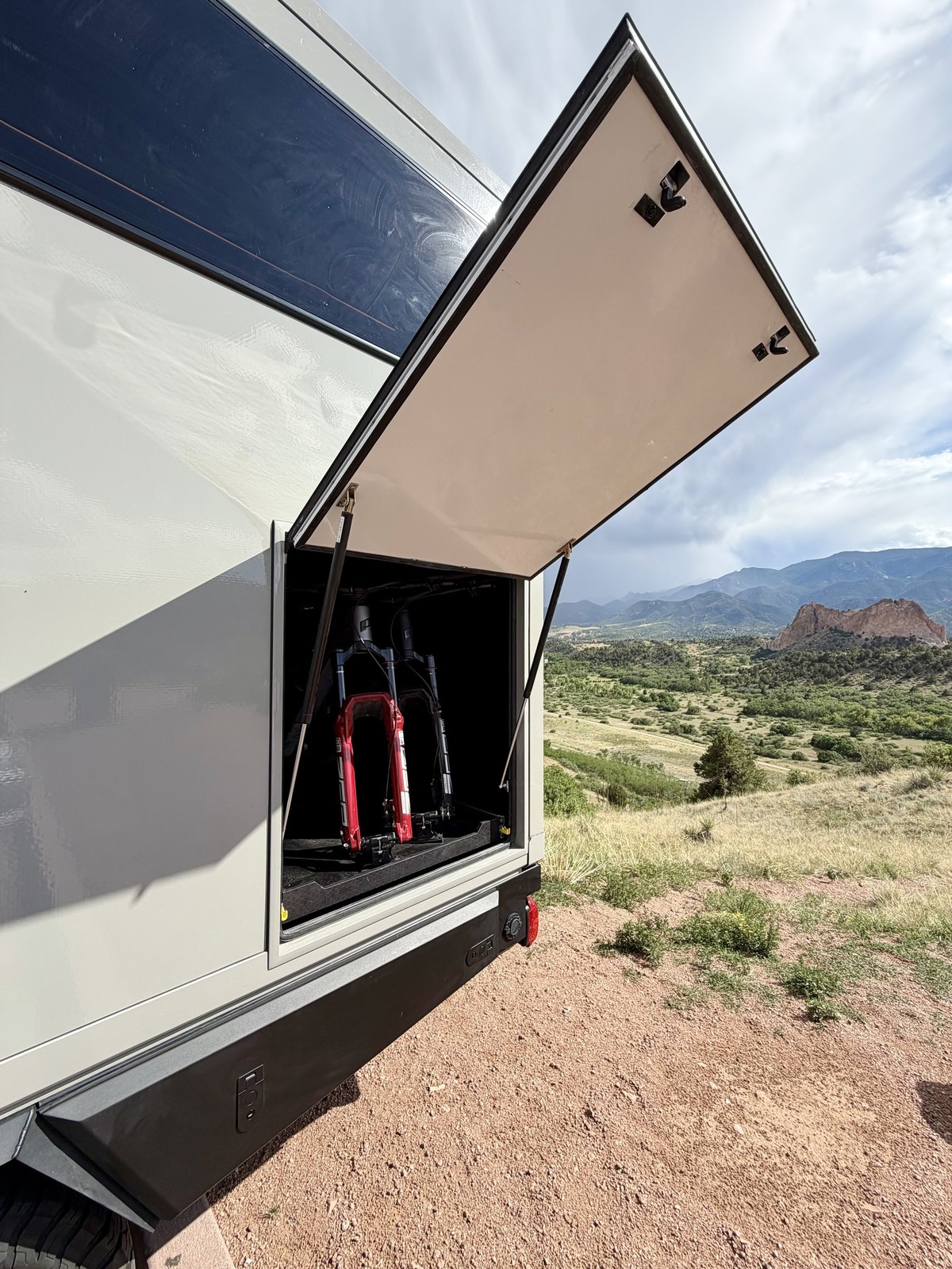 An open Nest exterior storage compartment with gear inside and mountains beyond.