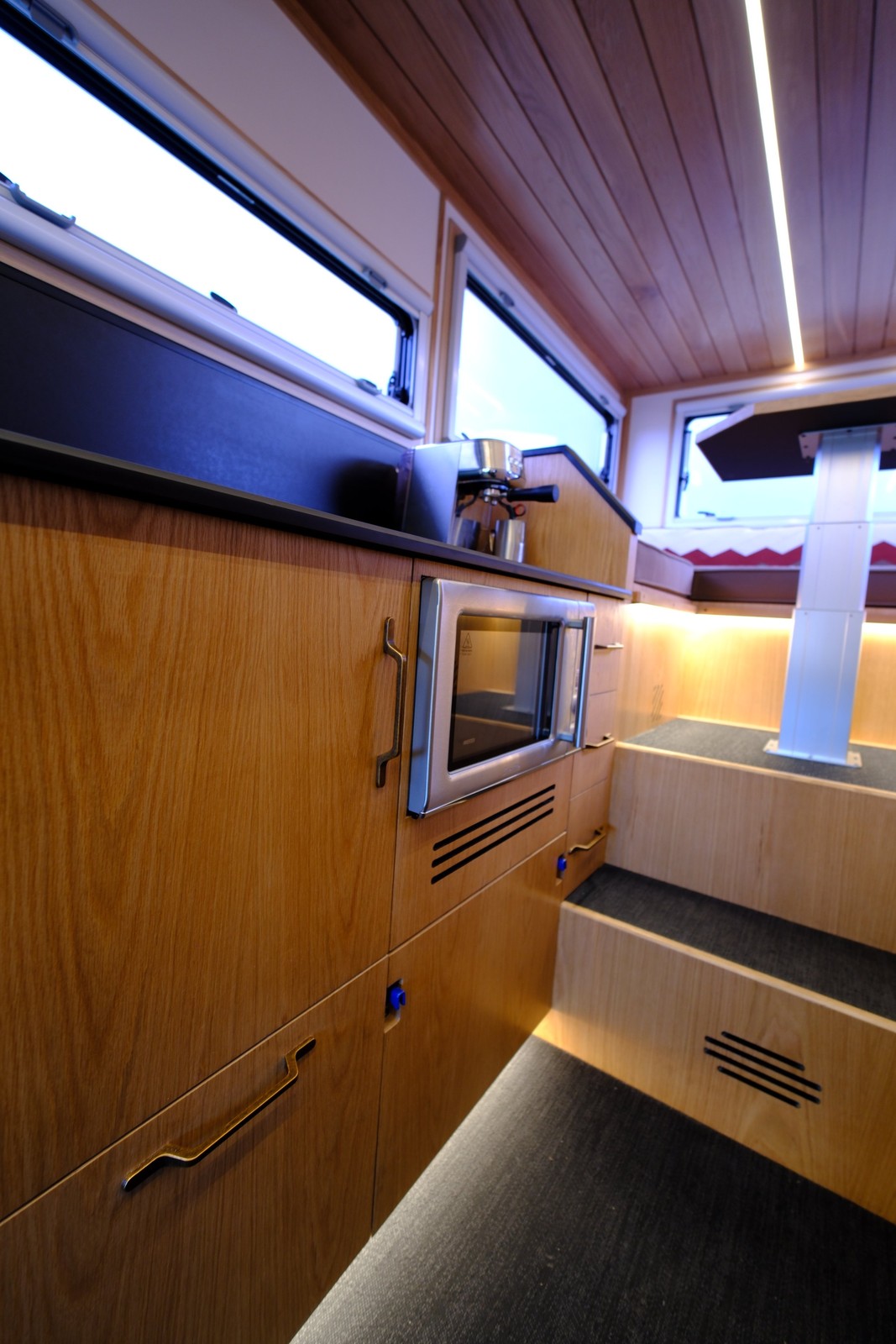 The Nest lower galley cabinets and microwave beside the steps to the rear dinette.