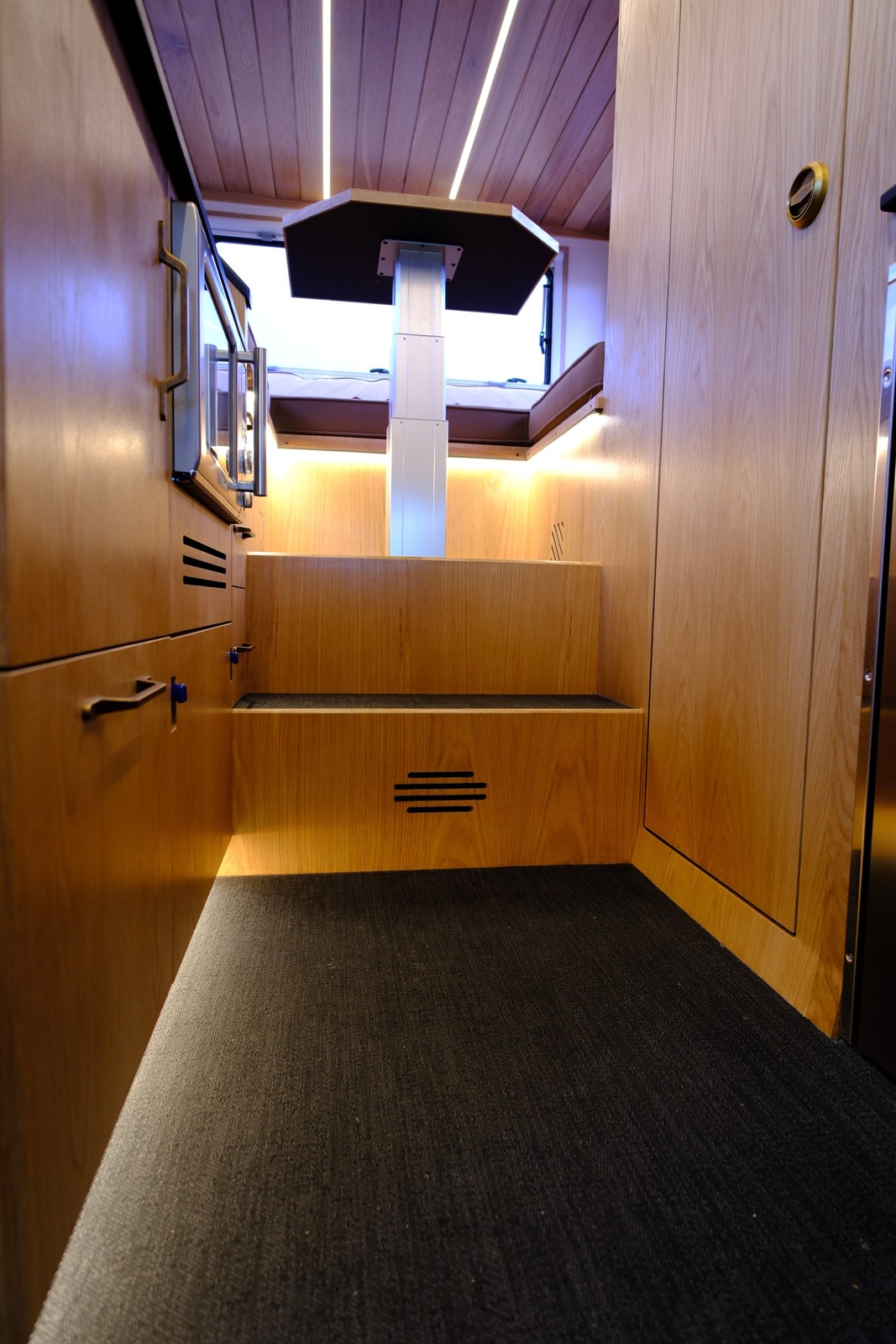 The Nest center aisle with wood cabinetry and steps leading to the rear dining area.