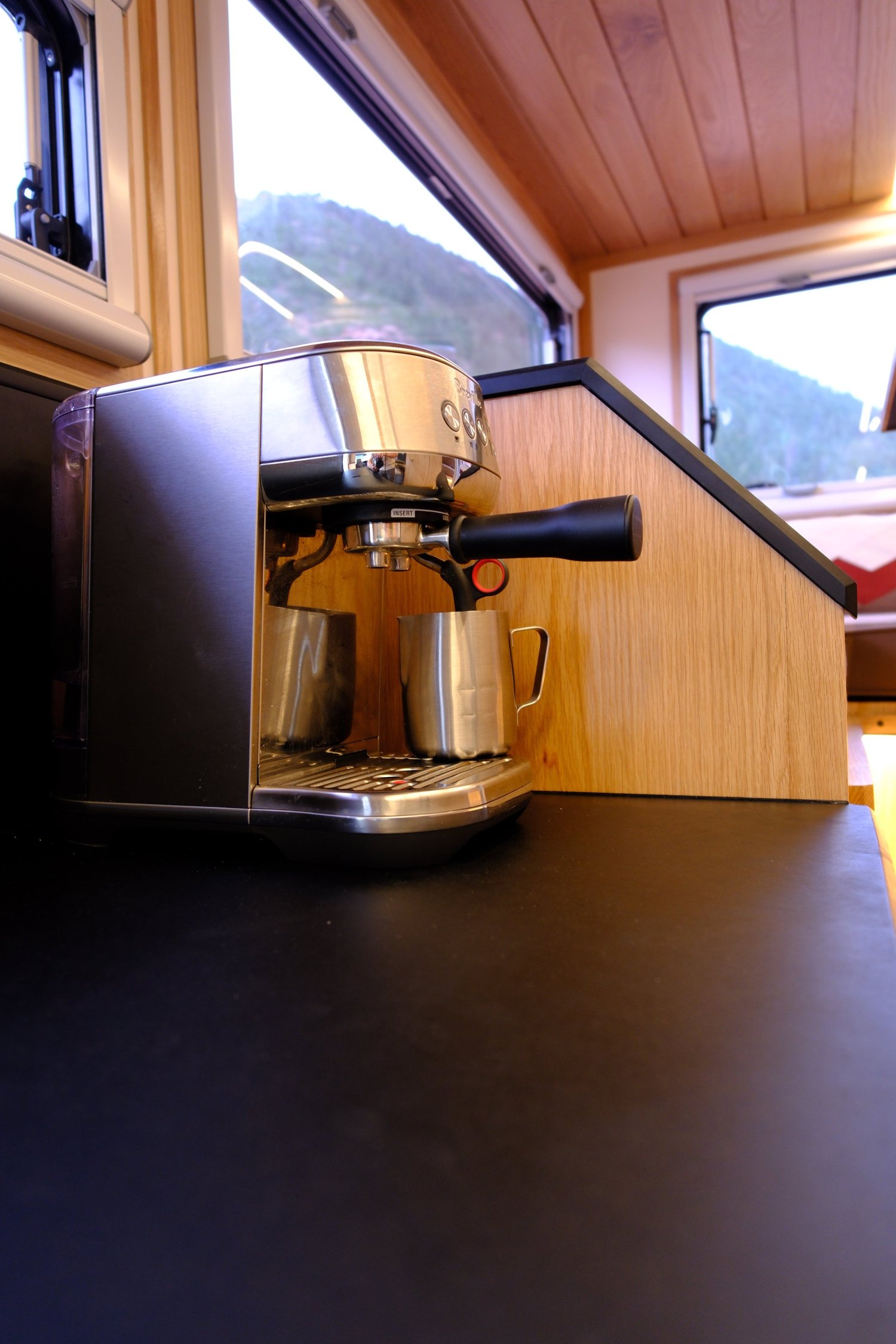 A coffee maker on the Nest black galley countertop beside wood cabinetry.