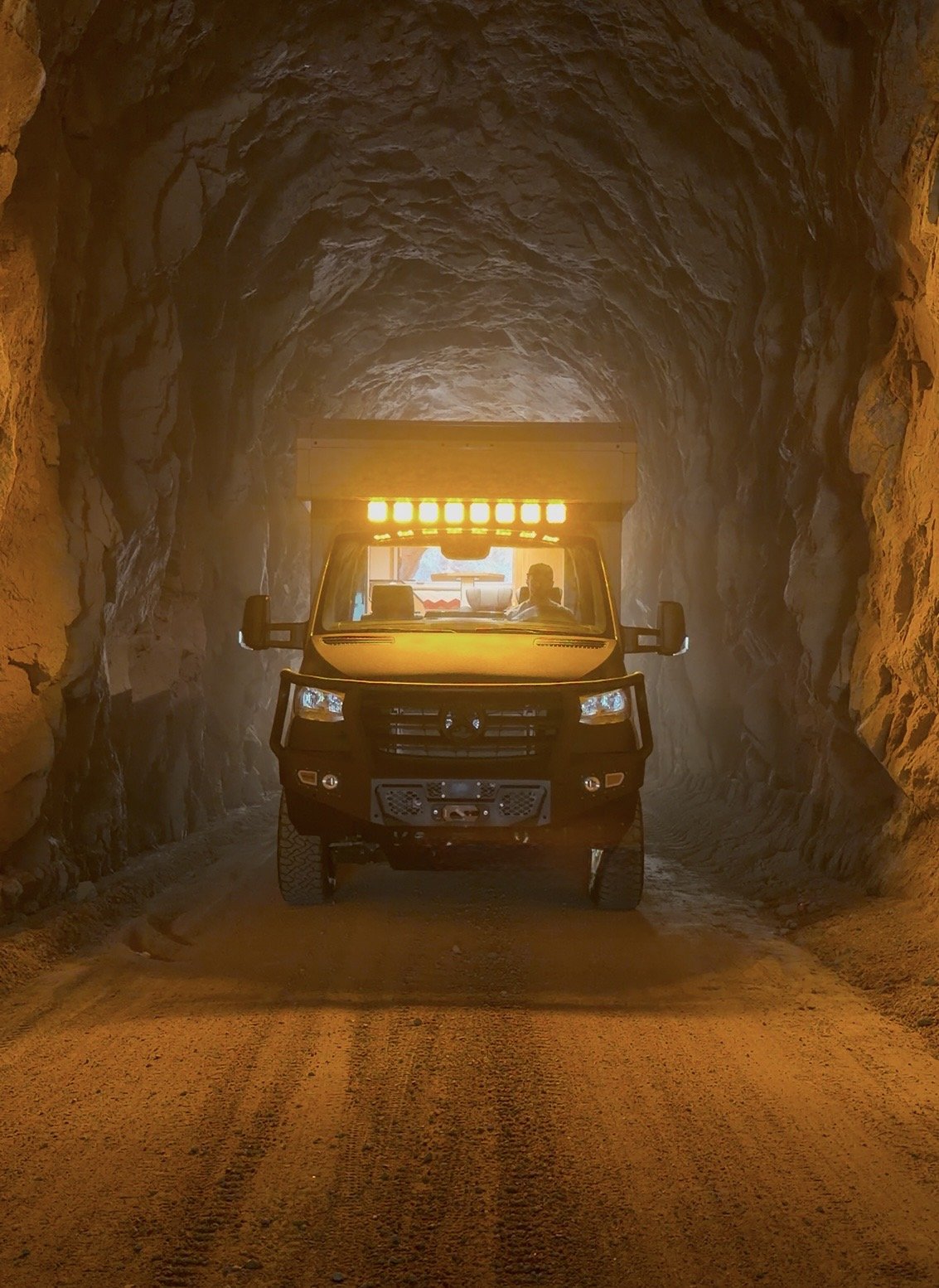 The Nest with amber roof lights in a rock tunnel.