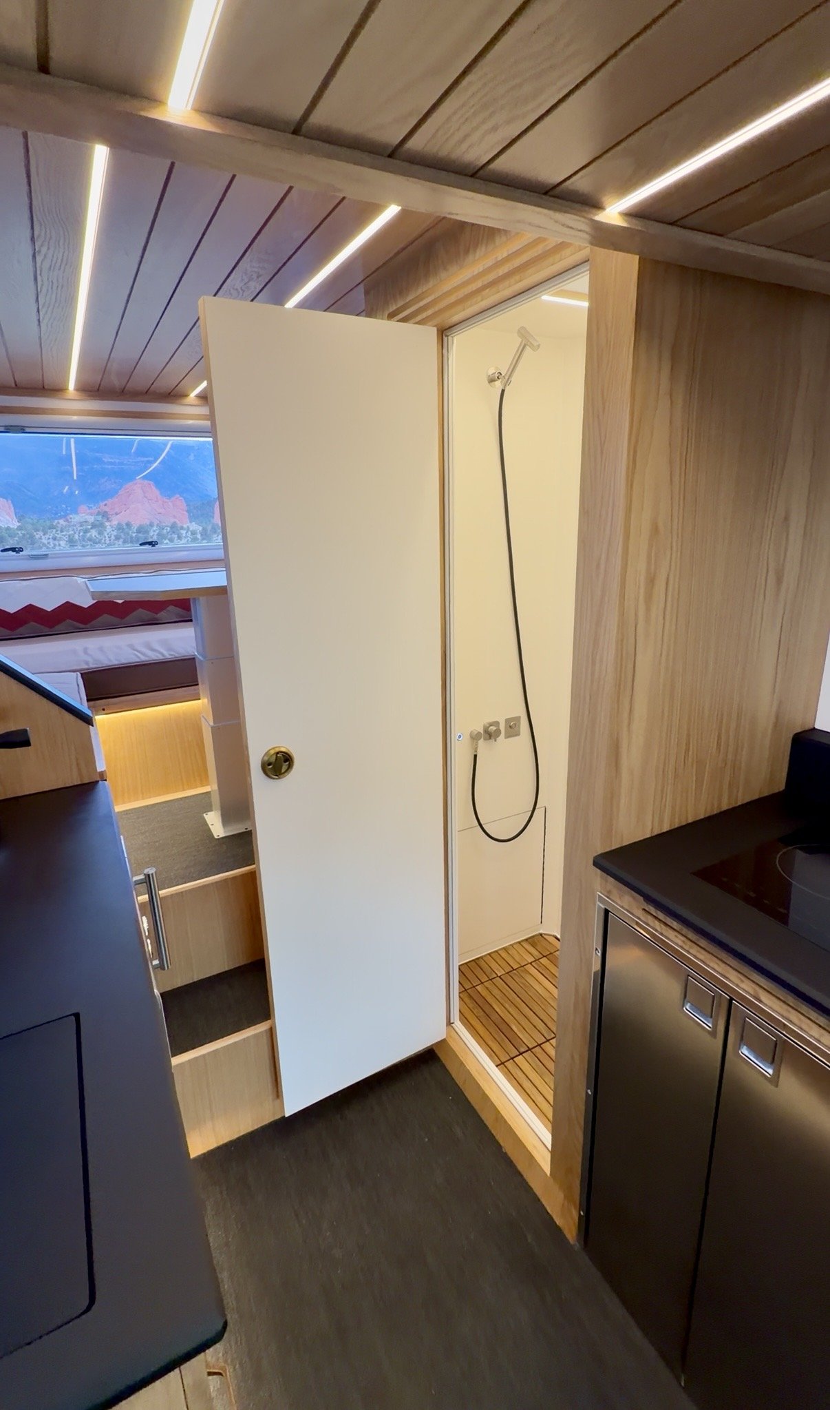 The Nest interior shower with its door open, wood trim and dark floor.